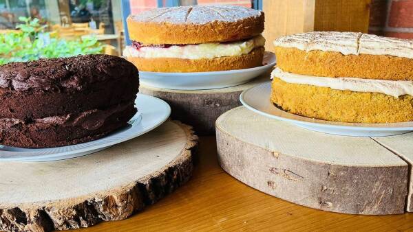 Three multi-layered cakes on a wooden table, each with different flavors and icing designs.