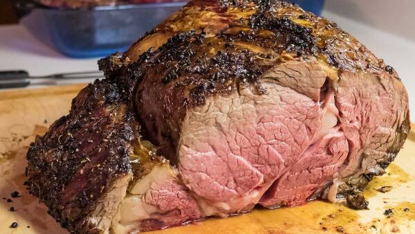 A large, well-marbled roast beef ready to be carved and served.