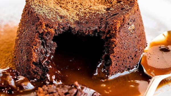Rich chocolate lava cake with a gooey caramel center, served on a dining table.